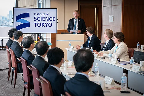 Man speaks to several people sitting at a table