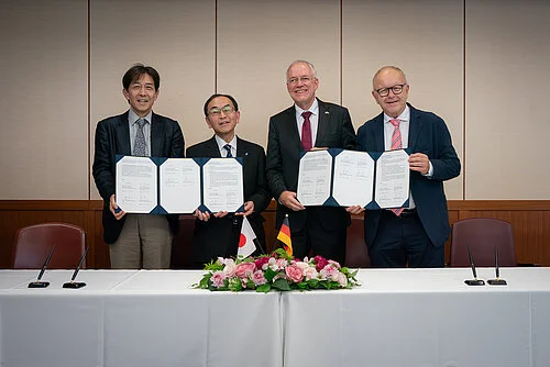 Four men hold up documents